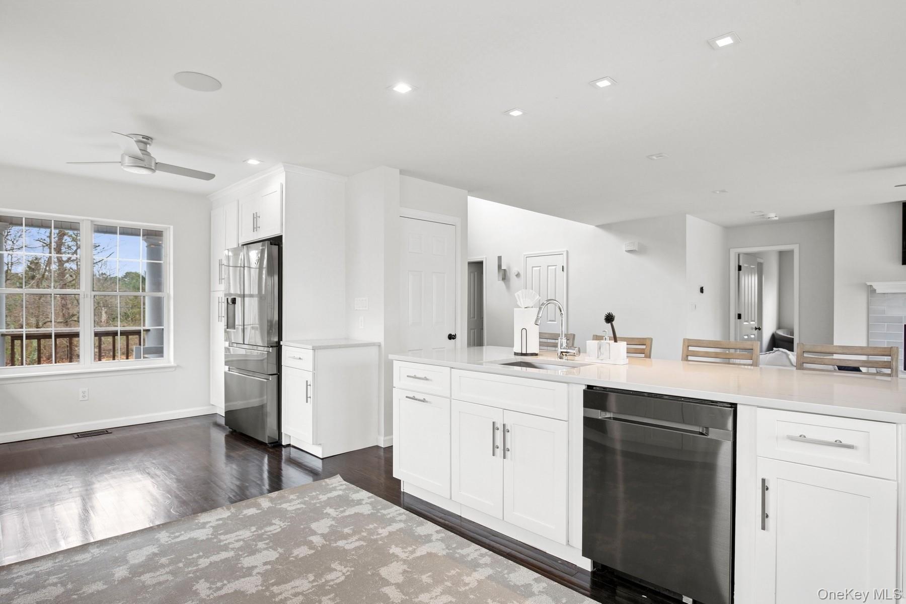 Kitchen featuring a sink, ceiling fan, dark wood-style floors, white cabinetry, and stainless steel appliances