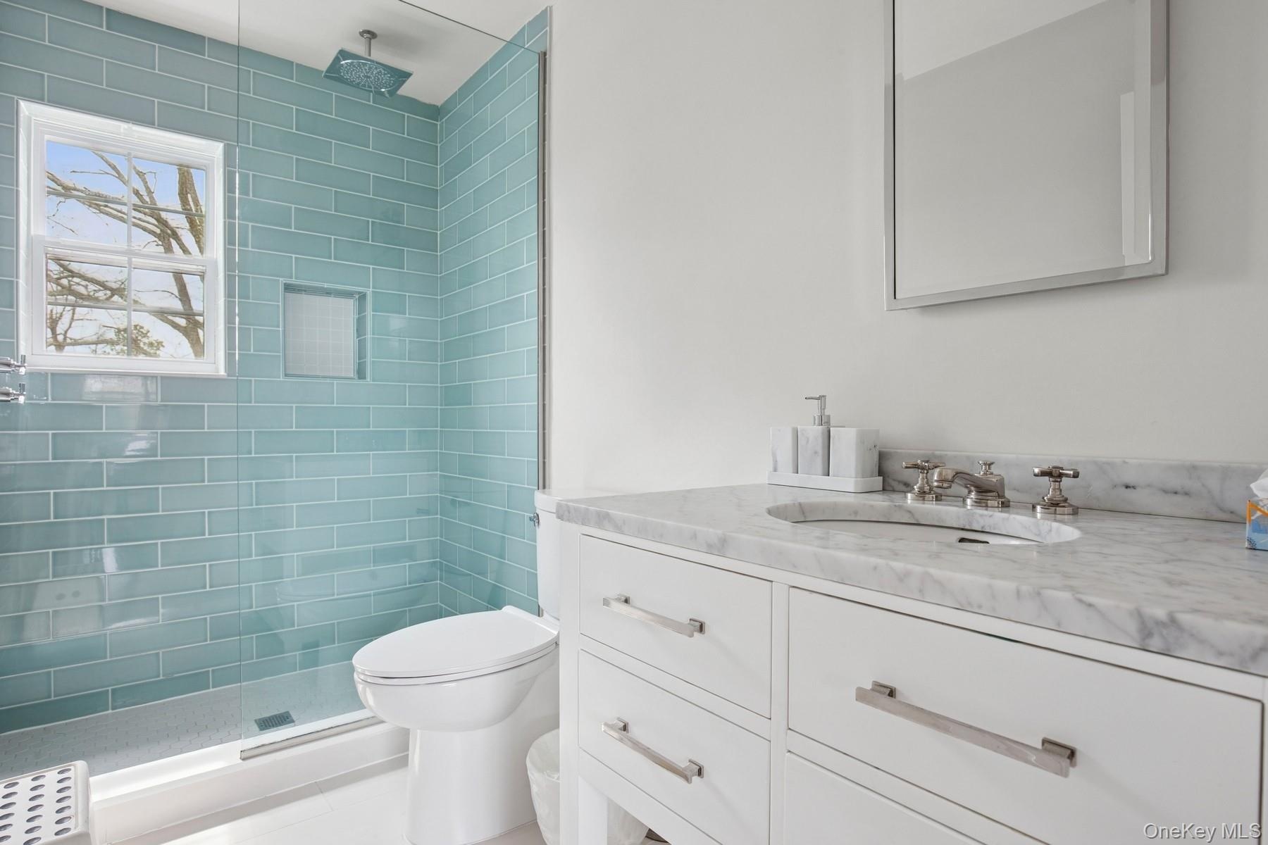 Full bathroom featuring a tile shower, visible vents, toilet, and vanity