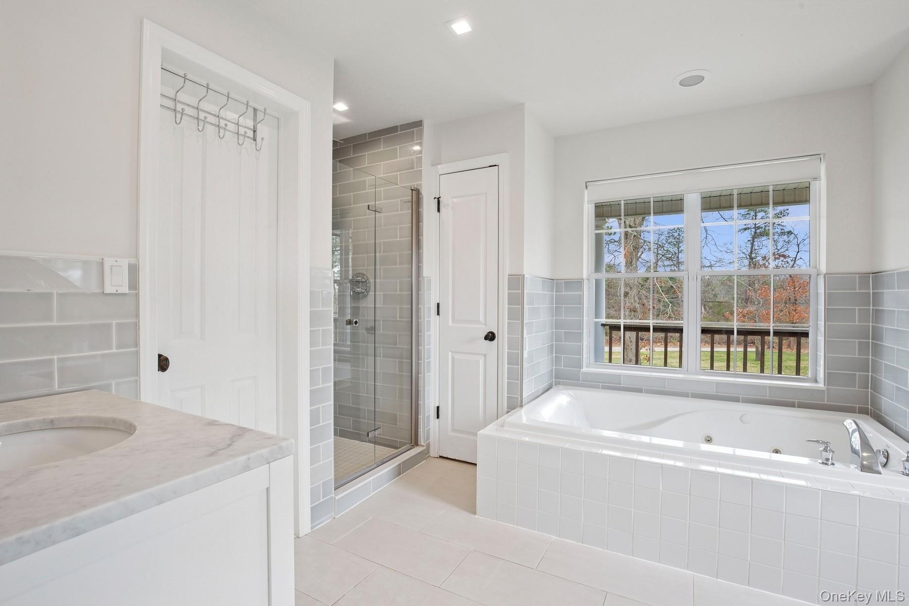 Bathroom with a stall shower, vanity, a tub with jets, and tile patterned floors