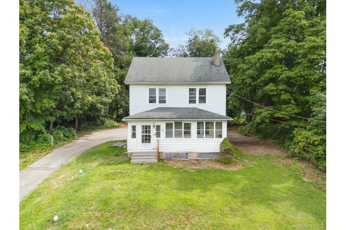 View of front of home with driveway, a chimney, a front yard, roof with shingles, and view of scattered trees