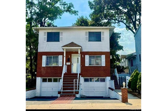 View of front of house with brick siding, an attached garage, and stairs
