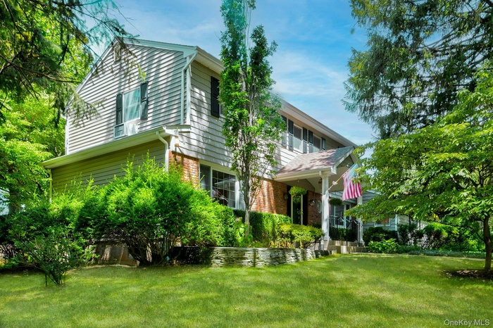 View of front of property with brick siding, a front lawn, and a balcony