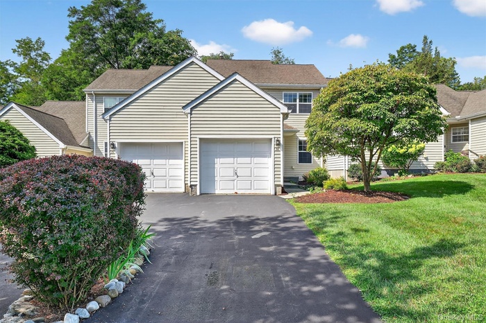 Traditional-style house featuring asphalt driveway, a front yard, and an attached garage