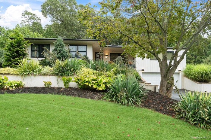 View of front facade featuring a front yard and a garage
