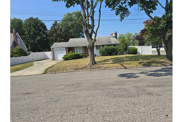 Ranch-style home featuring driveway, an attached garage, brick siding, and a chimney