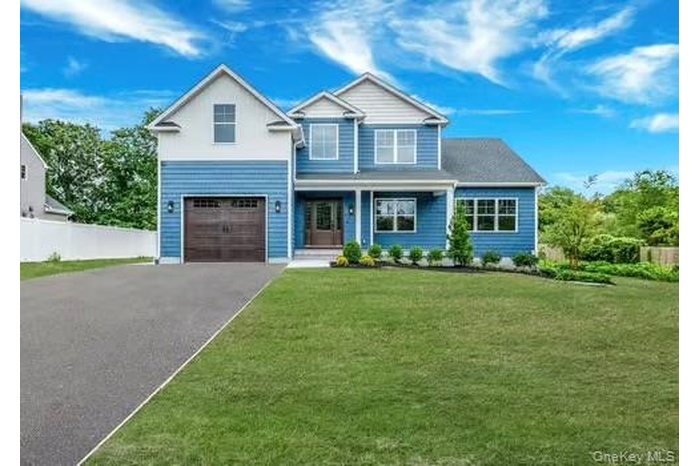 View of front facade featuring covered porch, asphalt driveway, and a garage
