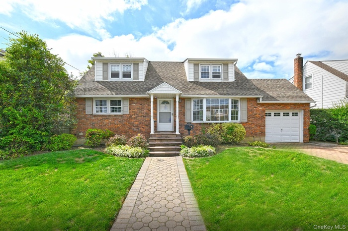 View of front of property with brick siding, a garage, concrete driveway, roof with shingles, and a front yard