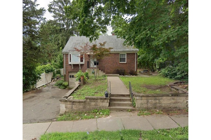 View of front of house with brick siding, driveway, a chimney, and an attached garage