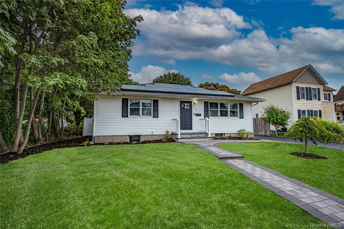 View of front of house featuring a front lawn and roof mounted solar panels