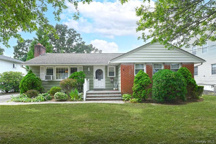 Ranch-style home featuring a front yard, brick siding, and a chimney