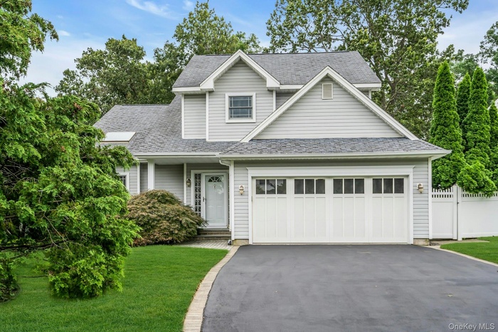 View of front facade with driveway and a shingled roof