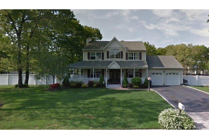 View of front of property featuring an attached garage, covered porch, driveway, and a chimney