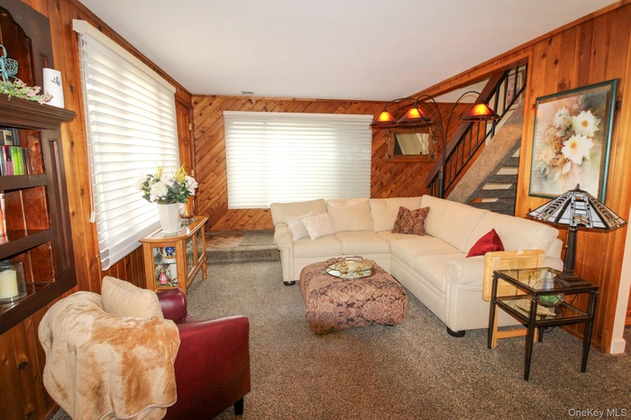 Living area featuring wooden walls, stairs, and carpet flooring
