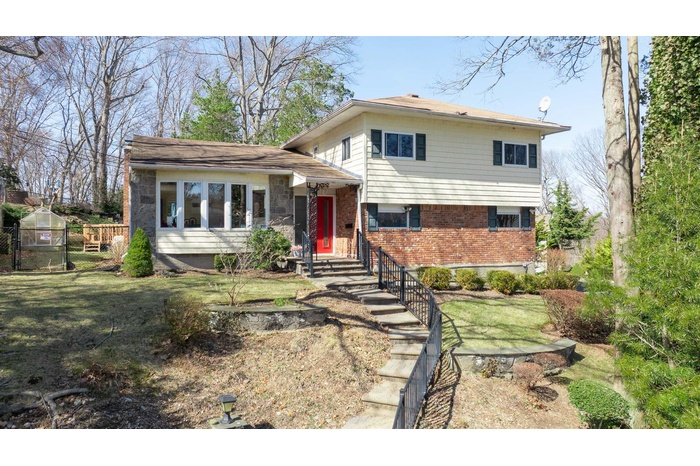 Split level home with brick siding, a front lawn, and fence
