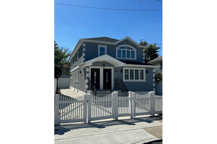 View of front of house featuring an outdoor structure, a fenced front yard, a garage, and a gate