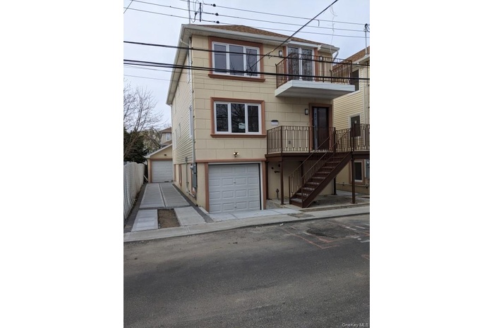View of front of property with a balcony, stairs, and an attached garage
