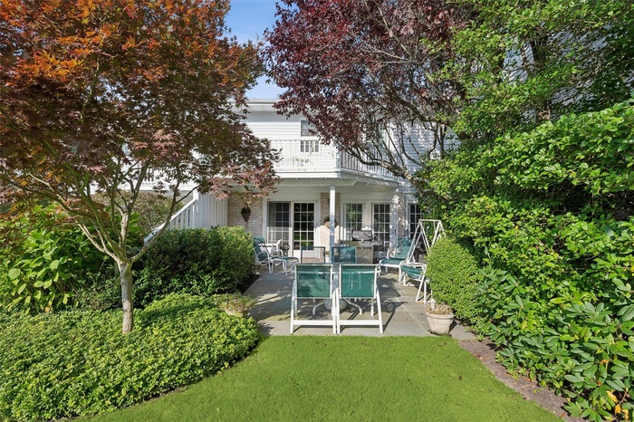 Rear view of property featuring bluestone patio, balcony, red maple and flowering plum tree.