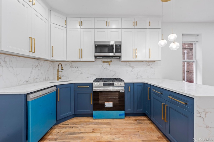 Kitchen featuring light stone counters, white cabinetry, stainless steel appliances, and blue cabinets