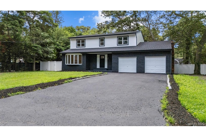 Traditional-style home with asphalt driveway, brick siding, roof with shingles, and an attached garage
