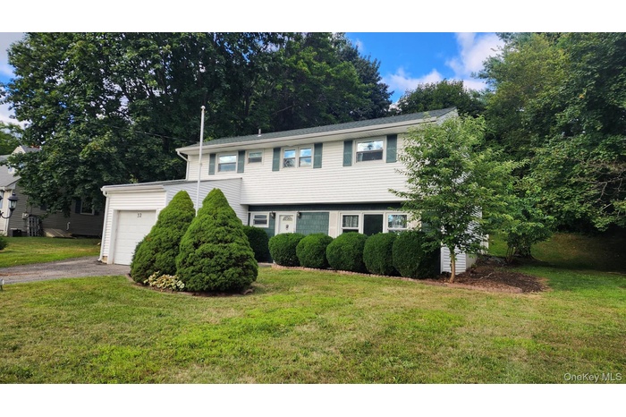 View of front facade featuring a garage, driveway, and a front lawn