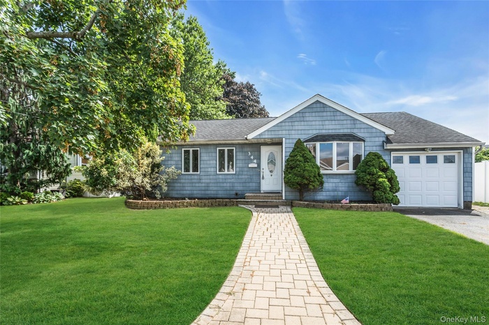Ranch-style home featuring roof with shingles, an attached garage, and a front lawn