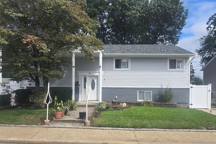 Raised ranch featuring a front lawn and roof with shingles