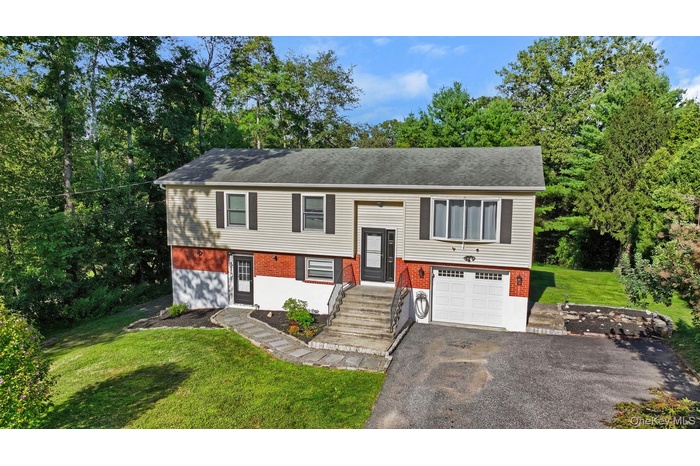 Bi-level home with a front yard, an attached garage, asphalt driveway, and brick siding