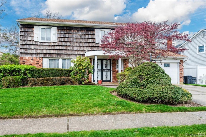 View of front of property featuring brick siding, a front yard, concrete driveway, and a garage