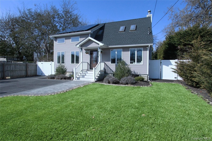 View of front of property featuring a gate, roof mounted solar panels, and a shingled roof