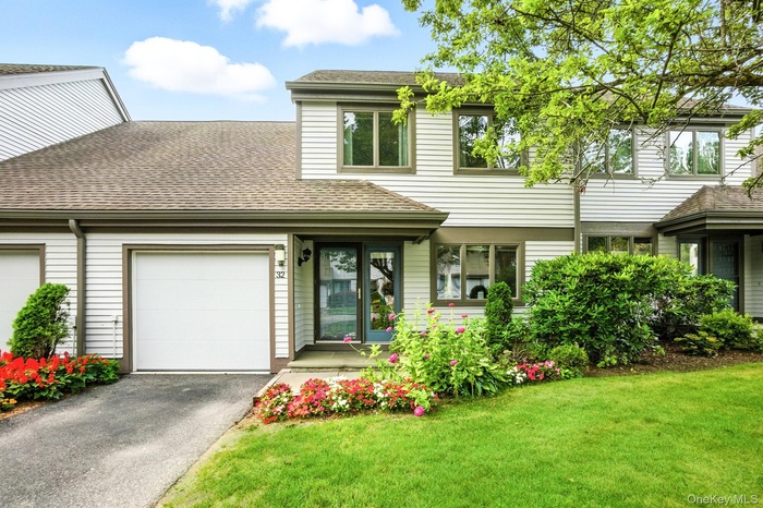 View of front of house with an attached garage, a shingled roof, driveway, and a front yard