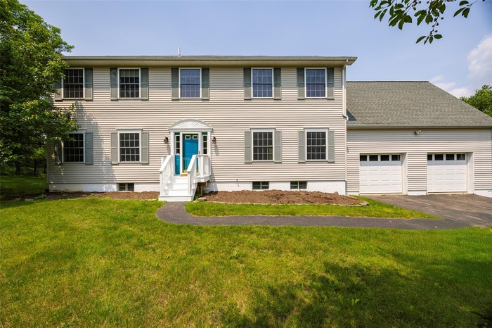 Colonial-style house featuring asphalt driveway, a front yard, and a garage