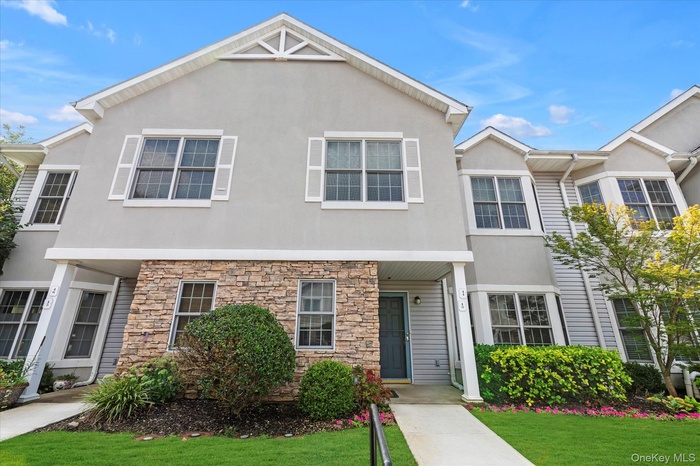 View of front of property with stucco siding, stone siding, and a front lawn