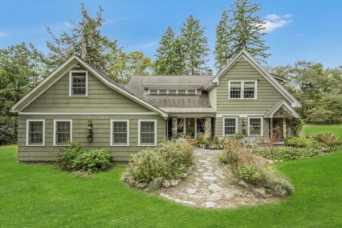 Back of house with a yard, stone siding, a chimney, and a shingled roof