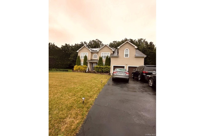View of front of property with a garage, asphalt driveway, and a front yard