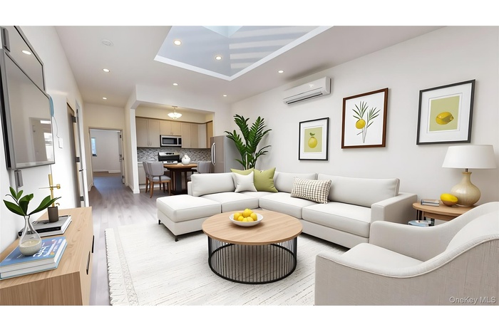 Living room with light wood finished floors, recessed lighting, an AC wall unit, a raised ceiling, and a skylight