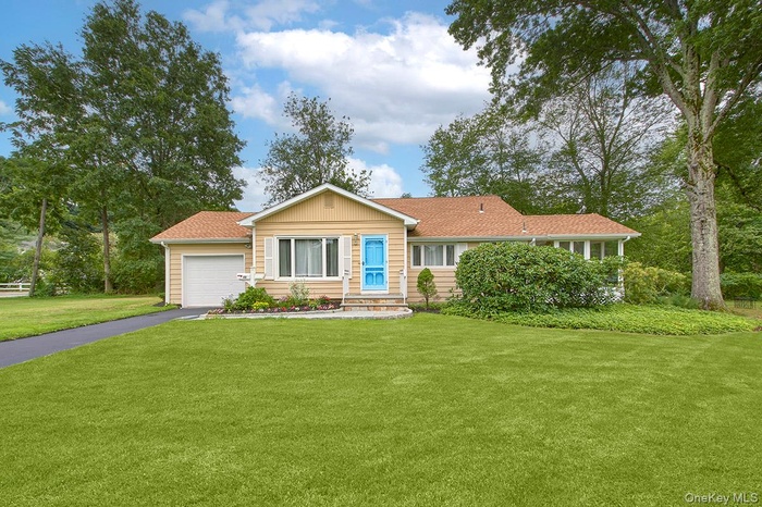 Ranch-style home with custom front door, level property a front lawn, attached garage