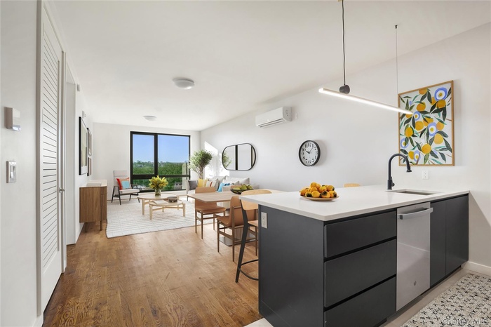 Kitchen featuring an AC wall unit, a sink, dishwasher, light countertops, and modern cabinets