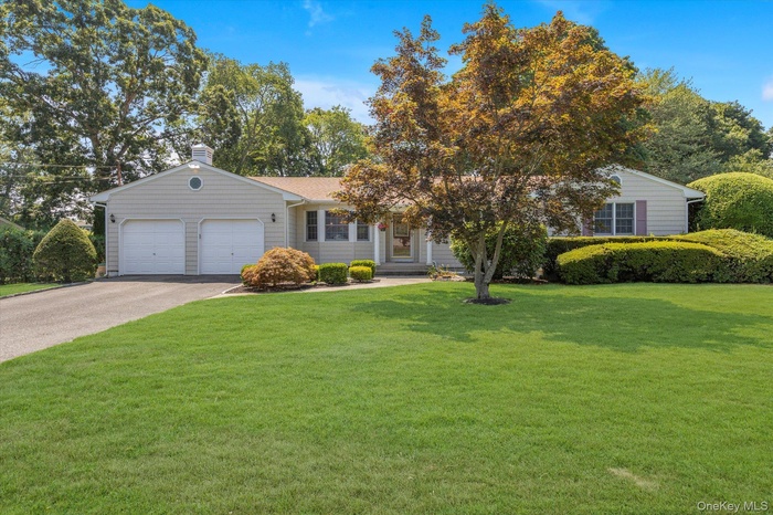 View of front of house with a garage, driveway, a front lawn, and a chimney