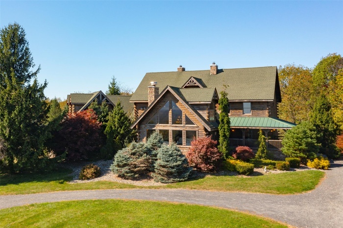 Log-style house featuring a standing seam roof, a chimney, a front lawn, and metal roof