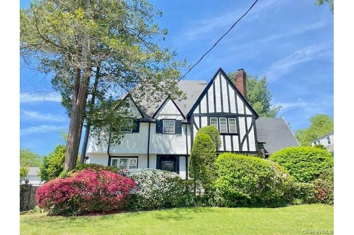 View of side of property featuring a yard, a chimney, and stucco siding
