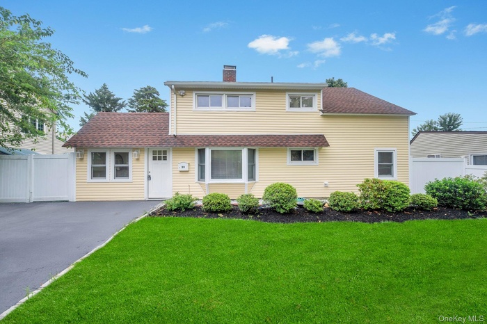 Traditional home with a chimney, roof with shingles, and asphalt driveway
