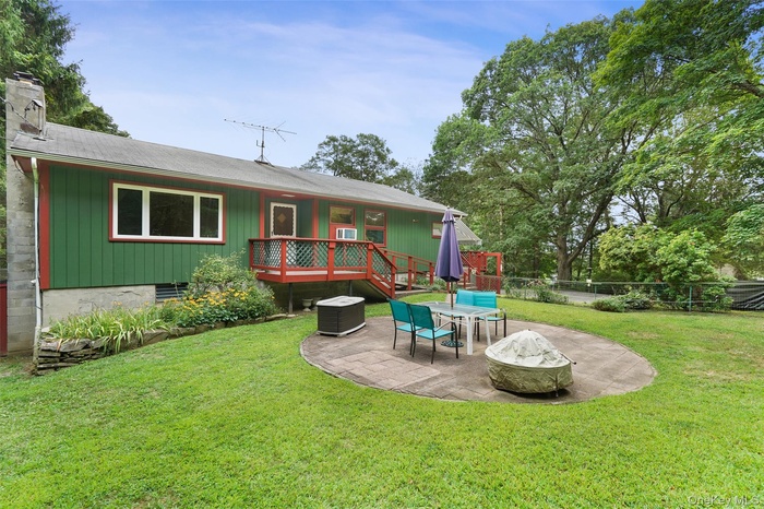 Front Side of property with a patio, a wooden deck, a chimney, and a shingled roof