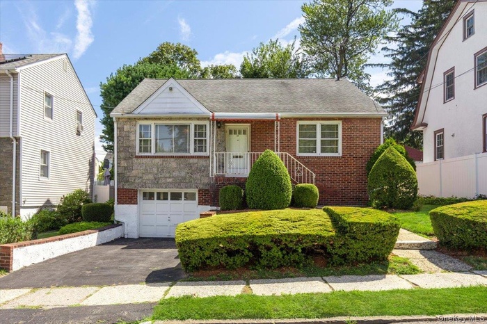 Welcome to 96 Rossiter featuring a driveway, a 2 car tandem garage, and brick siding with granite