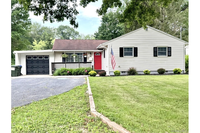 Single story home with asphalt driveway, an attached garage, a front yard, and a porch