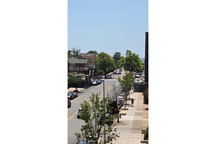 View of asphalt road with sidewalks, curbs, traffic signs, and street lighting