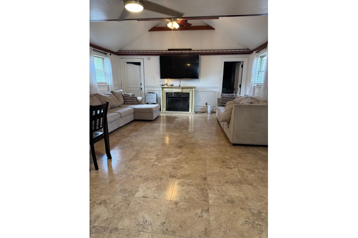Living room with healthy amount of natural light, a decorative wall, a fireplace, and ceiling fan