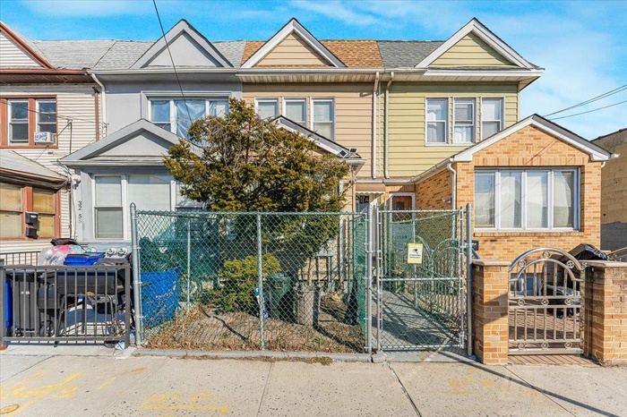 View of property with a fenced front yard, a shingled roof, a gate, and brick siding