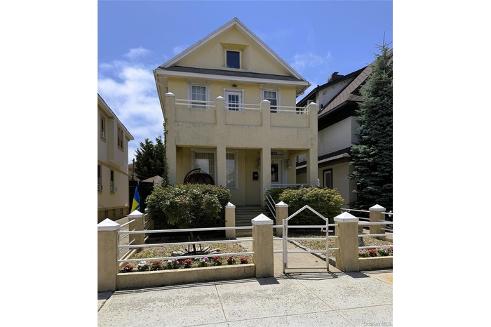 View of front facade featuring a gate, stucco siding, a fenced front yard, a balcony, and covered porch