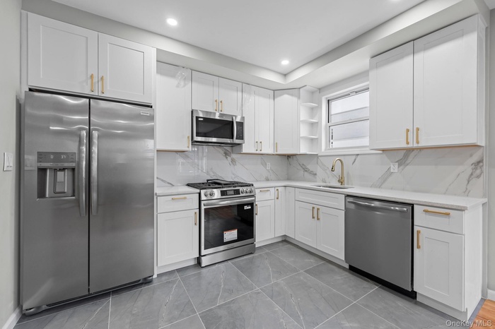 Kitchen with appliances with stainless steel finishes, tasteful backsplash, white cabinetry, open shelves, and recessed lighting
