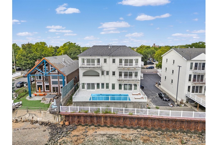 Back of property with a fenced backyard, a patio area, a hot tub, and a balcony